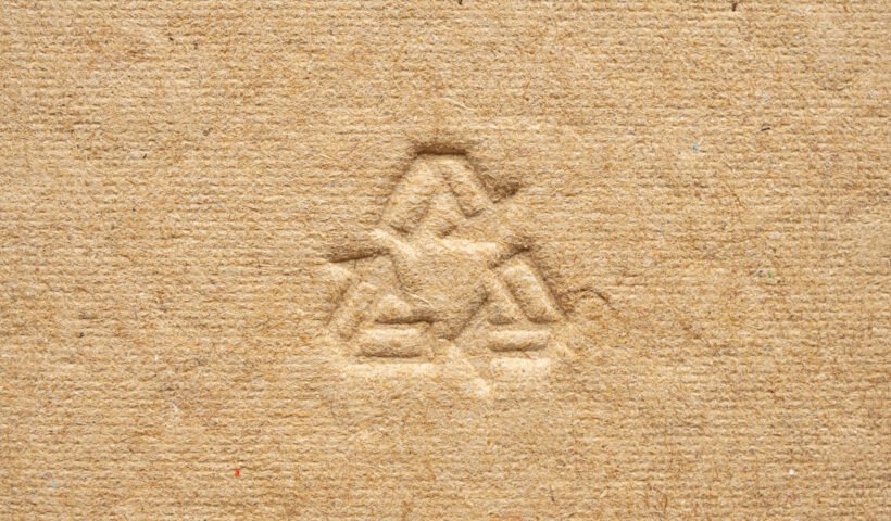 Descubre el Impacto del Cartón en la Sostenibilidad: Fabricación y Usos 5 a recycle symbol carved in a cardboard